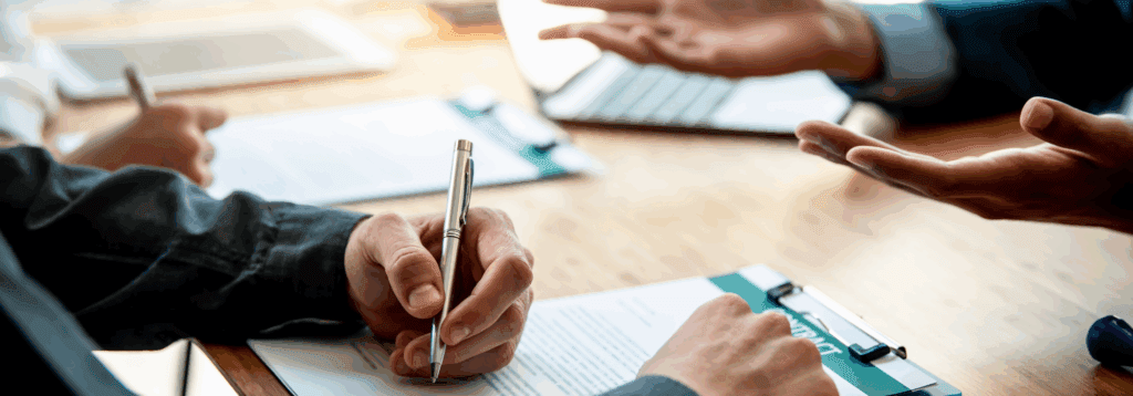 Hand signing contract on table
