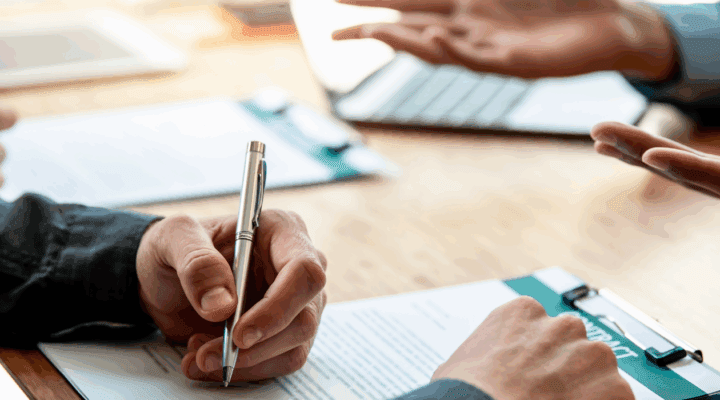 Hand signing contract on table